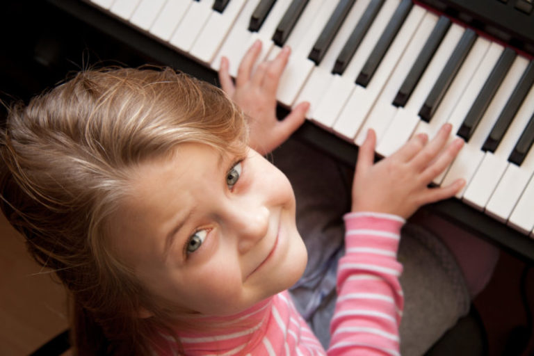 Young girl sitting at digital piano